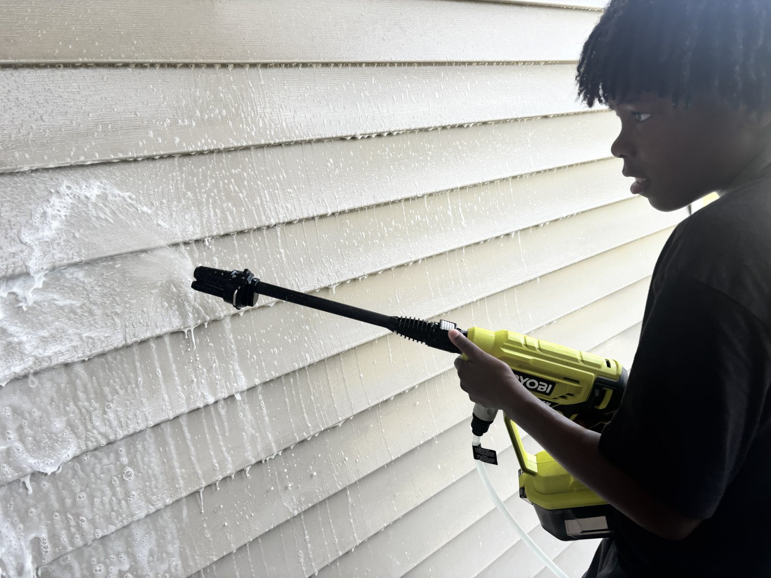 Rinsing the siding clean with the pressure washer